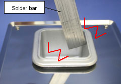 When a solder bar is hit against the pot while melting the solder.